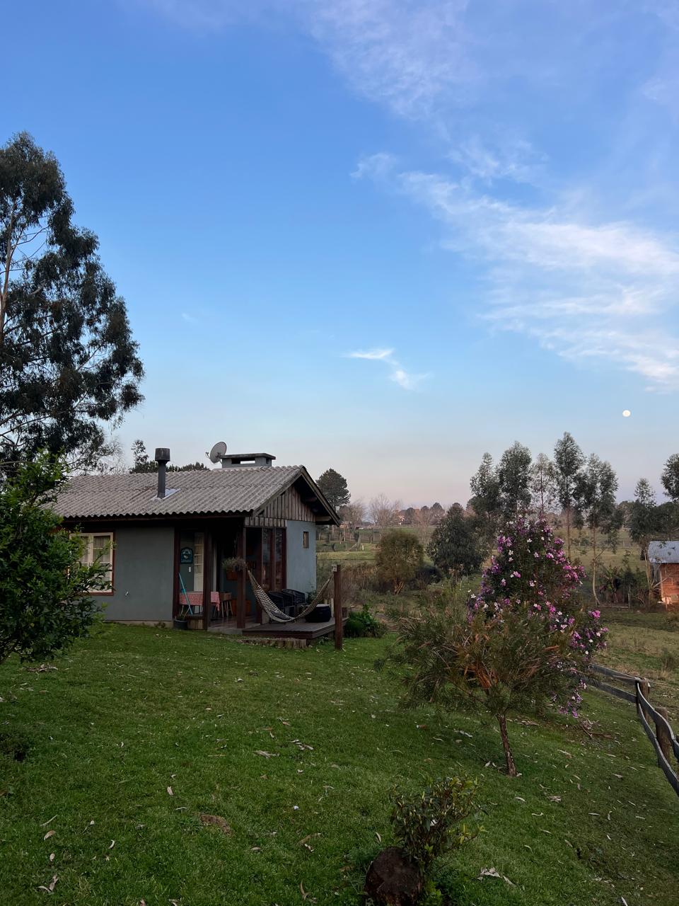 Chalé do Ninho da Coruja com varanda e rede, cercado pelo campo